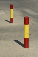 Red and yellow bollards with painting chips on dirty asphalt