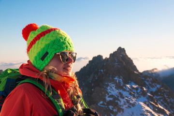 Smiling attractive young woman hiking in winter high mountains with backpack