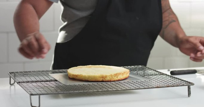Male confectioner making sponge cake with custard cream vanilla cream on a rack