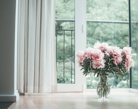 Fototapeta Glorious pastel pink bouquet of peonies in glass jug on  floor by window.  Flowers in interior design. Cozy home.