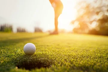 Poster Im Rahmen Golfer-Action zum Gewinnen nach langem Putten des Golfballs auf dem grünen Golf. Sonnenuntergang Zeit. © weerasak
