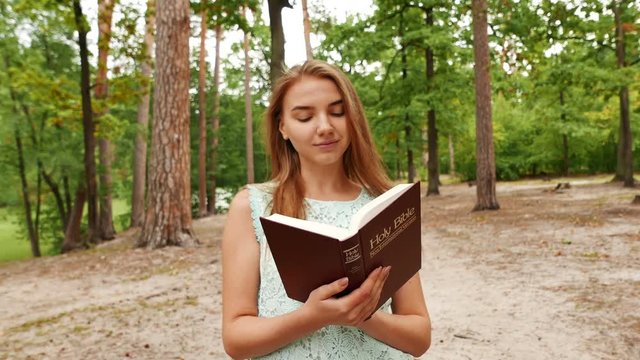 4k.Young  girl  walk with Bible in park. Christian team  steady shot