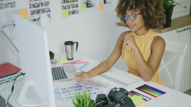 Stylish young woman in eyeglasses editing photos working at creative desktop in modern office looking confident and successful.