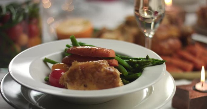 Serving steamed vegetables and roasted chicken on white round porcelain plates during a Christmas party