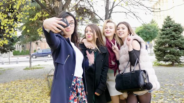 SLOW MOTION of group of girl friends taking a selfie in autumn city. Posing outdoors