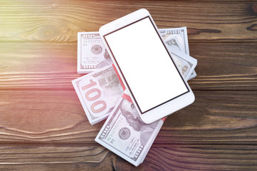smartphone, packs of dollars on a wooden table background