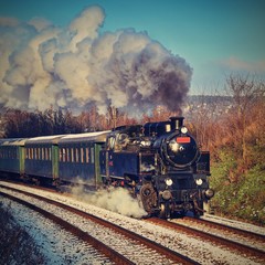 Fototapeta premium Beautiful old steam train with wagons running on rails at sunset. Excursions for children and parents on festive special days. Czech Republic Europe.