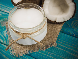 Coconut oil and fresh coconuts on a wooden table.