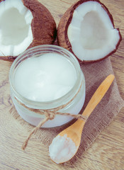Coconut oil and fresh coconuts on a wooden table.
