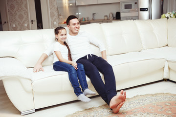 Attractive happy young family, father and daughter watching TV