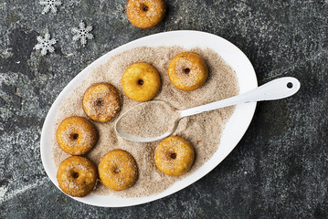 Appetizing ruddy traditional donuts with sugar and cinnamon on an oval dish on a gray grunge trendy...