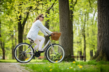Fototapeta premium Urban biking - woman riding bike in city park 