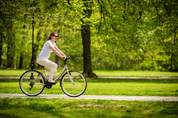 Urban biking - woman riding bike in city park 