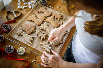 Woman making Christmas gingerbread cookies in kitchen