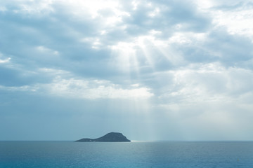Fototapeta na wymiar Grosa Island Silhouette Iluminated by sun ray through the clouds - La Manga del Mar Menor, Cabo de Palos, Cartagena and San Javier, Murcia, Spain, Europe