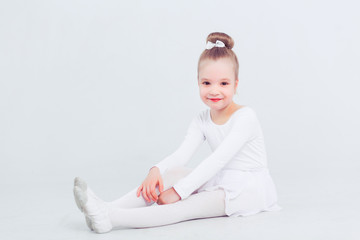 Little child girl dance ballet at white background. Portrait of small ballerina smiling and looking at camera