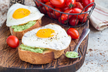 Open sandwiches with mashed avocado and fried egg, horizontal, copy space