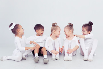Obraz premium Group of kids boys and girls dancing at a white class room or studio smiling and hugging together