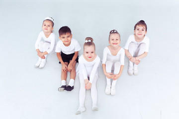 Fototapeta premium Cute little kids dancers on white background. Choreographed dance by a group of small ballerinas practicing at a classical ballet school