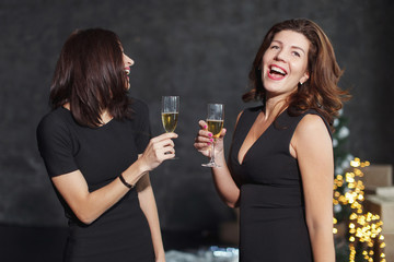 Beautiful girls in evening dresses with glasses of champagne to celebrate the New year