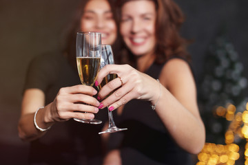 Beautiful girls in evening dresses with glasses of champagne to celebrate the New year