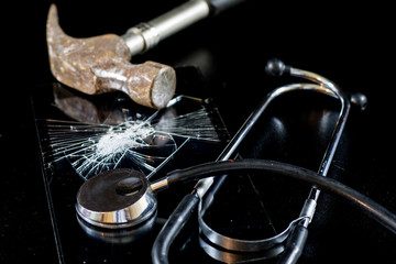 Broken tablet with broken screen and stethoscope in repair. Black table.