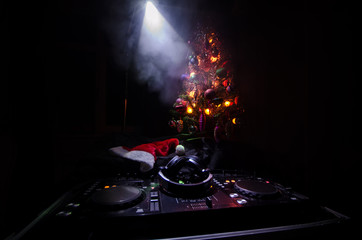 Dj mixer with headphones on dark nightclub background with Christmas tree New Year Eve. Close up...