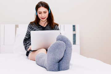 Woman using laptop on white bed at home