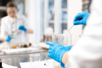 Small business people at work. Young woman working at the laboratory of cosmetic production. Mixing components. Young technologist making face care creams. Private small cosmetic products factory.