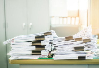 Paper business documents of unfinished stacked on office desk.
