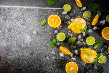 Fototapeta na wymiar Vitamin summer refreshing drinks. Citrus punch with oranges and lime, with mint sprigs, chilled with ice. On black stone table, with ingredients, copy space top view