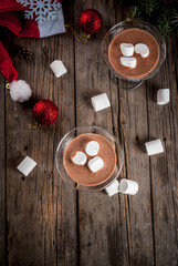 Ideas for Christmas party drinks, homemade Hot Chocolate Martini cocktails with marshmallow, on old rustic wooden table with christmas decorations, copy space top view