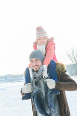 Vater lächelt mit Tochter auf dem Rücken