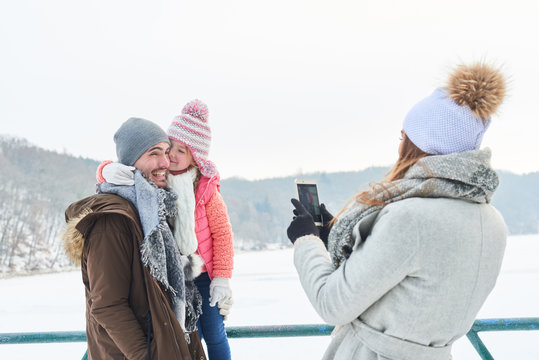 Frau fotografiert Mann und Tochter im Winter