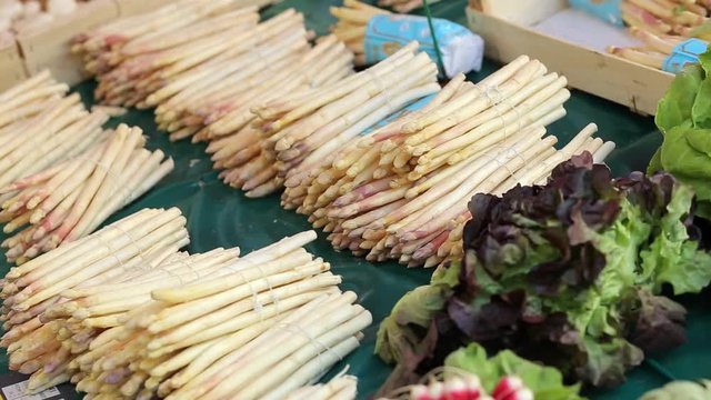 Pan video of vegetables stand with fresh white asparagus bunches, radish and artichokes at the farmers market place in Dieppe, France. Regional cuisine, natural healthy food and abundance concept
