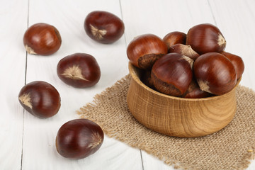 chestnut in wooden bowl on white wooden background