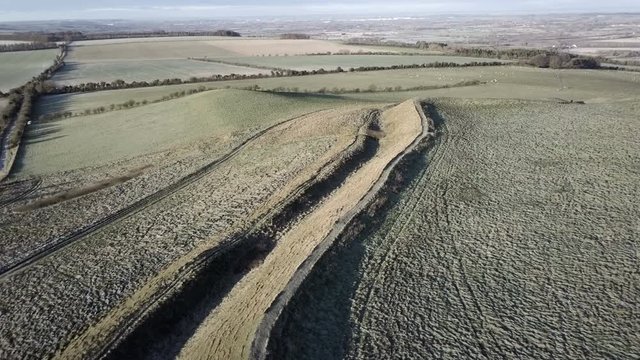 Aerial view over an ancient Motte and Bailey relief on a frozen winter morning at dawn in Oxfordshire England