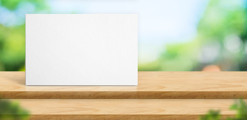 Blank poster on step wood table top food stand with blur green natural park tree background bokeh light,Mock up for display or montage of product,Banner for advertise on online media.
