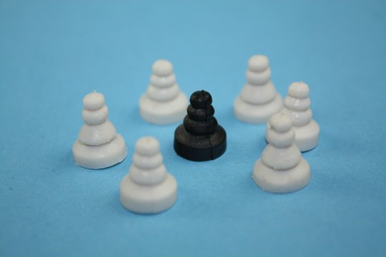 Racism or bullying concept photo with white chess pawn surround a black one.