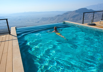 The girl in the pool in the beautiful mountain landscape. SPA hotel in the mountains. Oman.
