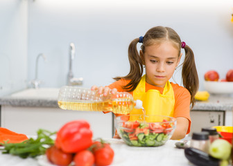 girl pour sunflower oil in a salad in the kitchen