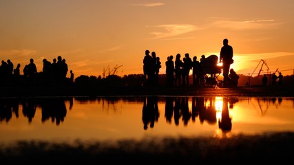 Group of people silhouette reflects on the water sunset time in Riga, Latvia