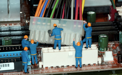 Motherboard Repair - Miniature construction worker figurines posed as if working on a computer motherboard.