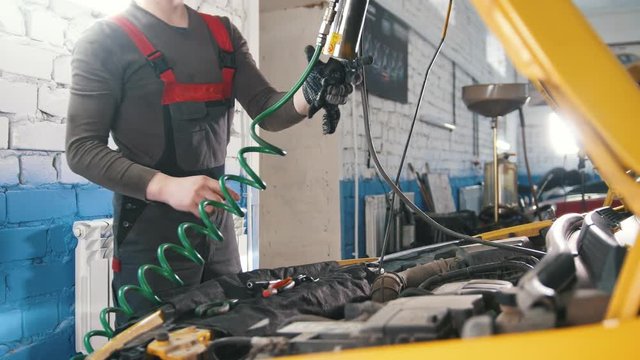 A mechanic checks the electrical in the hood of the car- repairing in engine compartment