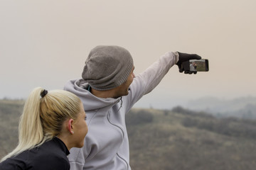 Young couple taking selfie by mobile phone at nature before jogging