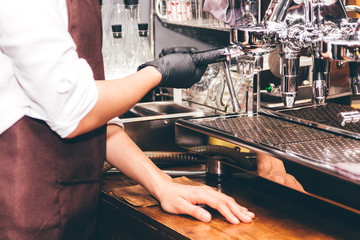 Women Barista using coffee machine for making coffee in the cafe