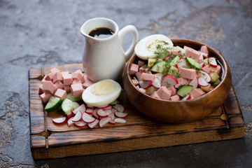 Okroshka or traditional russian cold soup with kvass on a wooden serving tray with some of its...