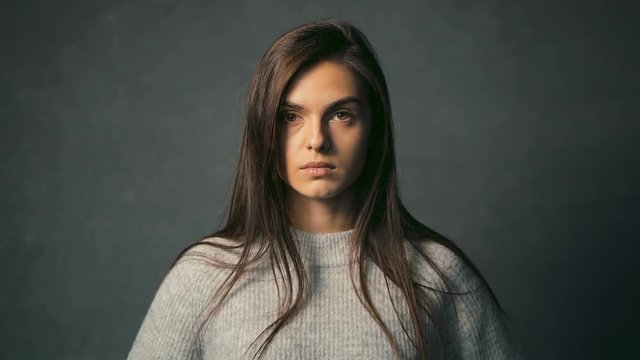 Portrait of pretty dark-haired girl smiling joyfully in the grey background, isolated shot