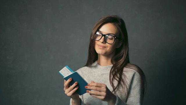 Attractive female traveller with passport and ticket in hands thinking about the holiday, isolated shot