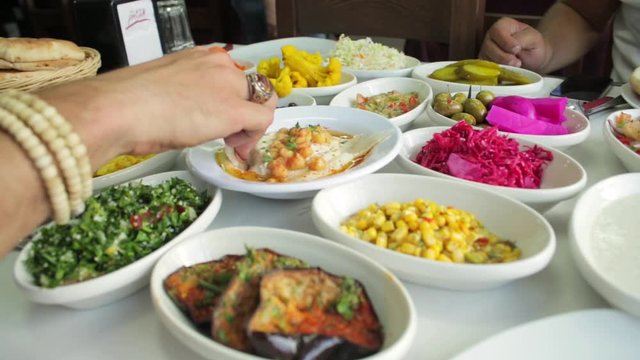 Middle east food plates and dishes. Arrangement of different arabic food specialties on a table. Especially vegetables like olives or carrots but also hummus, tabouleh and fried eggplant. 